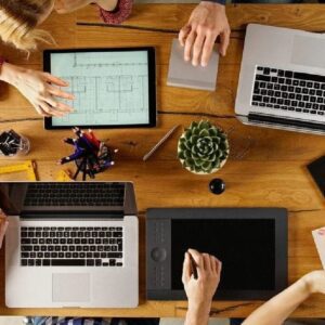 A group of people sitting around a table with laptops.