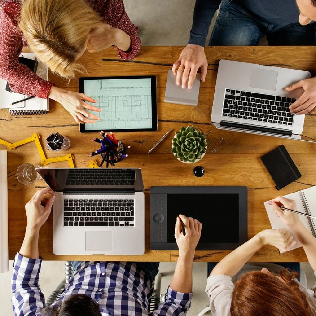 A group of people sitting around a table with laptops.