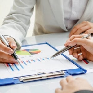A group of people sitting at a table with pens and paper.