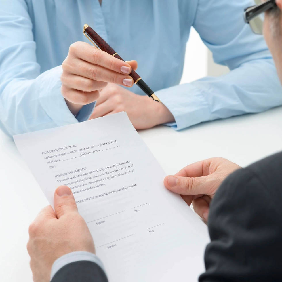 Two people are sitting at a table and one is holding a pen.